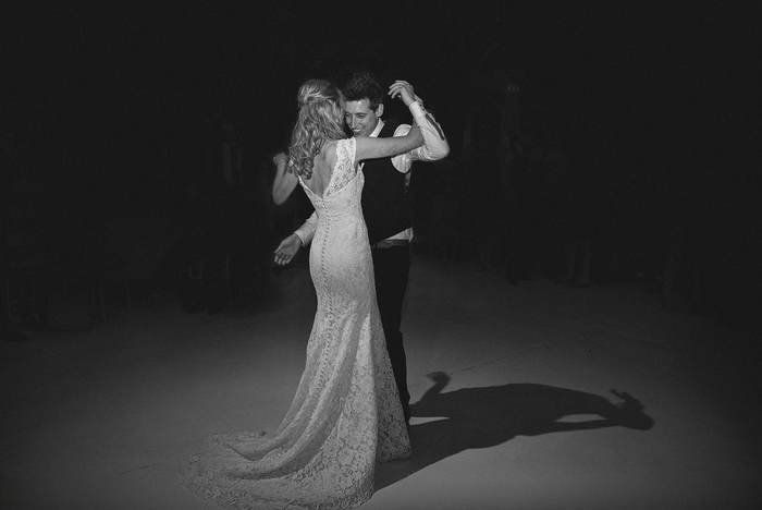 A couple sharing their first dance in the dark, lit by a single light