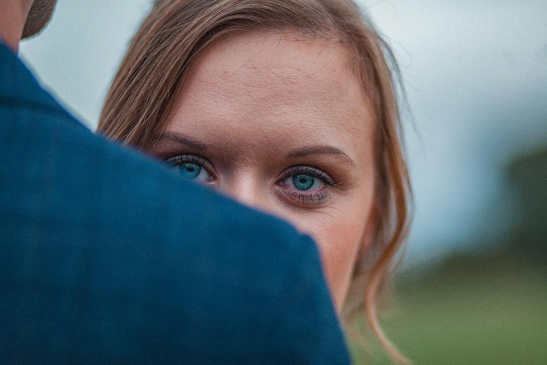 A bride's blue eyes peeking over her groom's shoulder