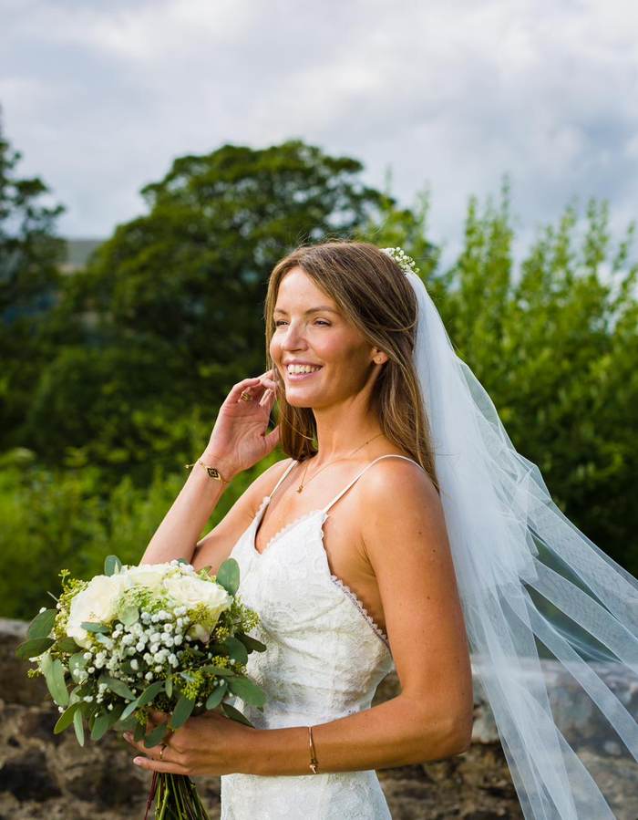 Bride laughing in the sunshine with her veil flowing behind her