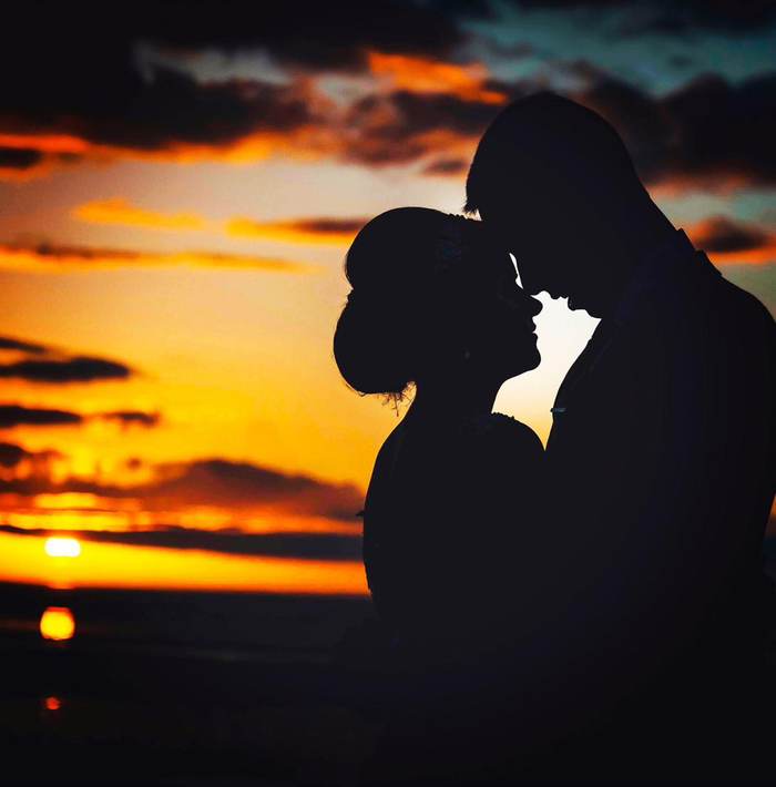 A couple silhouetted against a burning orange sunset