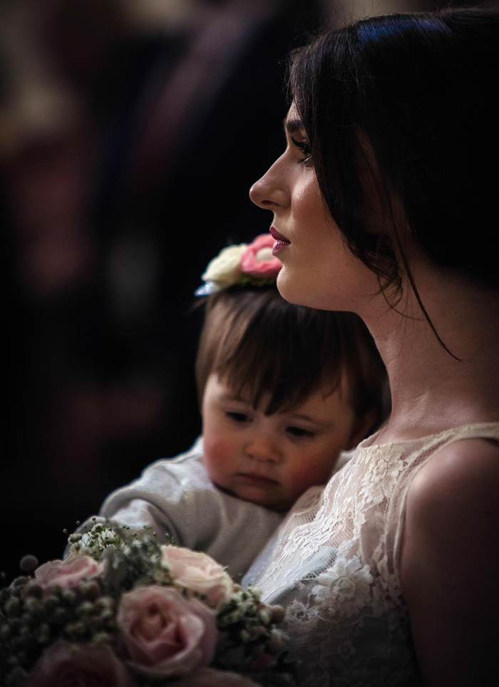 A woman in shadow holding a young child at a wedding